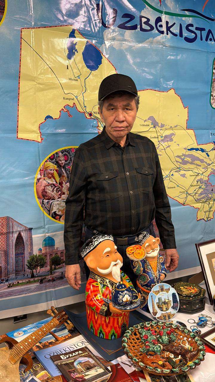 Visitor beside a cultural display table with a map and handicrafts