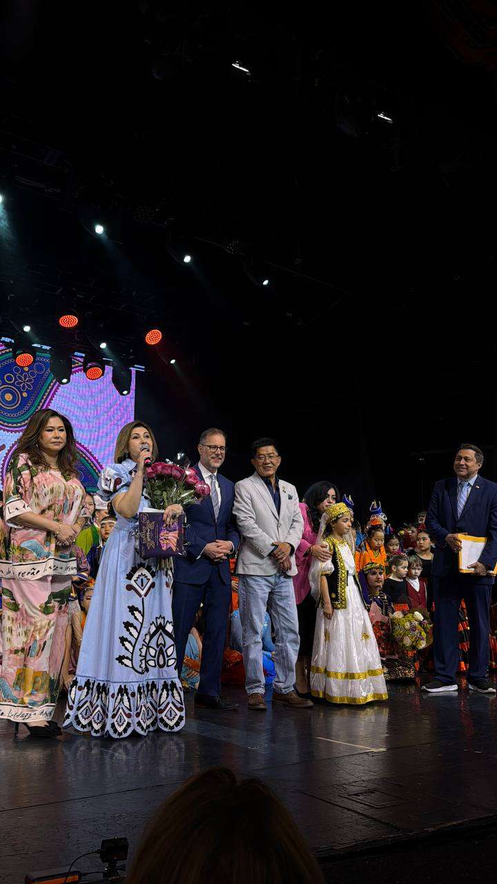 Performers and organizers with flowers on stage at a celebration