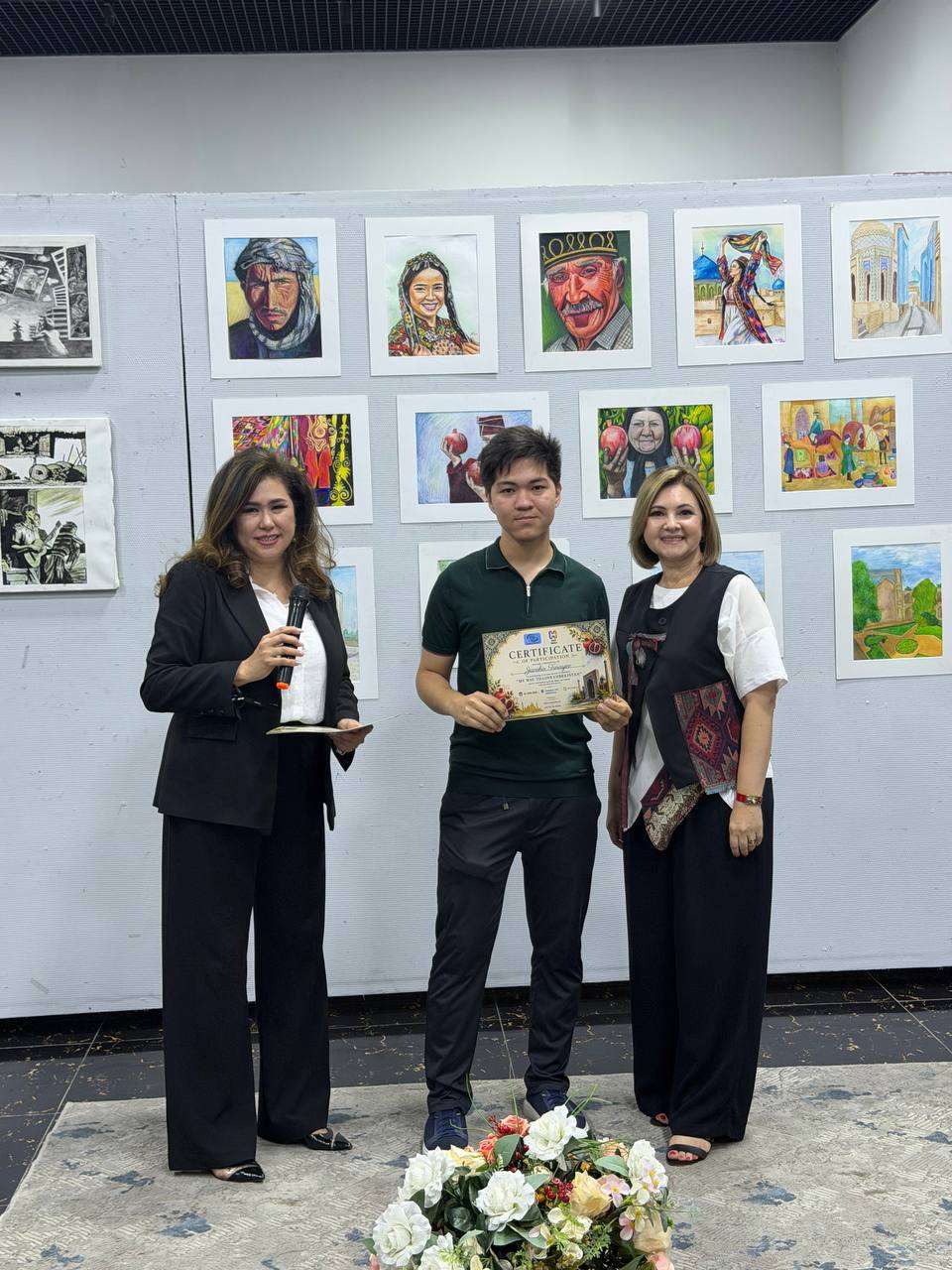 Certificate presented to a young artist at an exhibition, paintings displayed behind