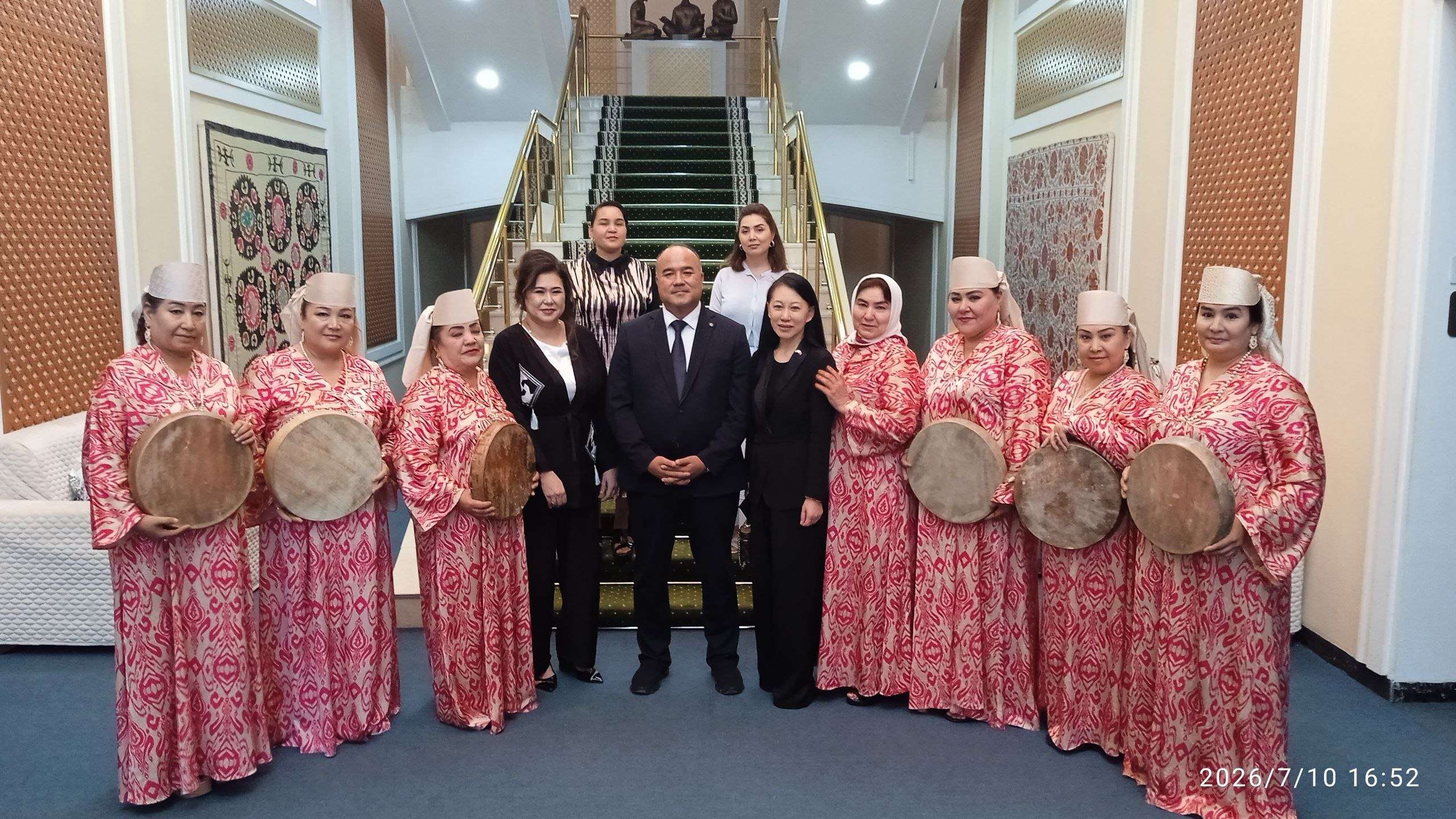 Drummers in traditional patterned dress welcoming a delegation in a decorated hall