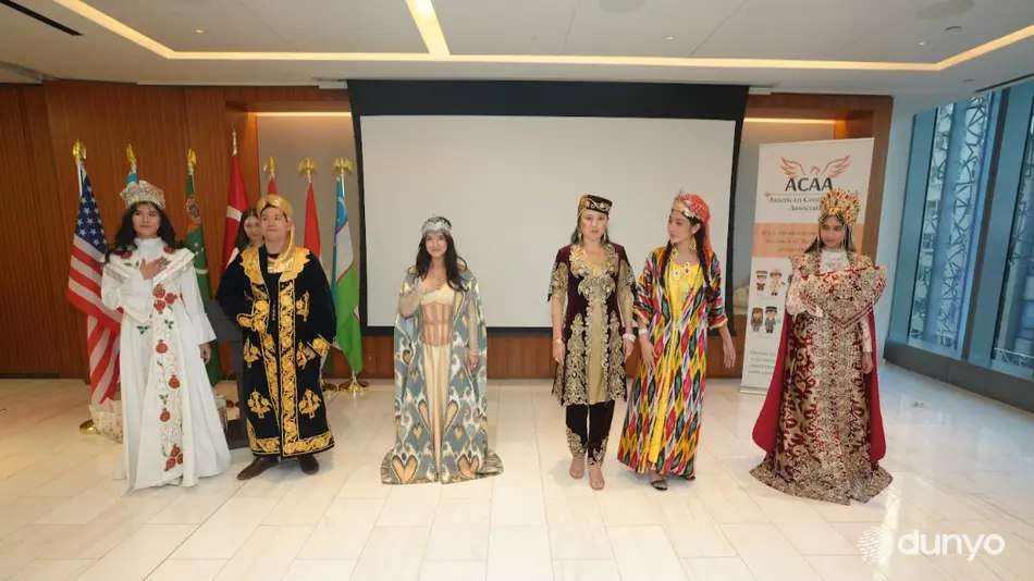 Models in traditional gowns presented on stage beside national flags