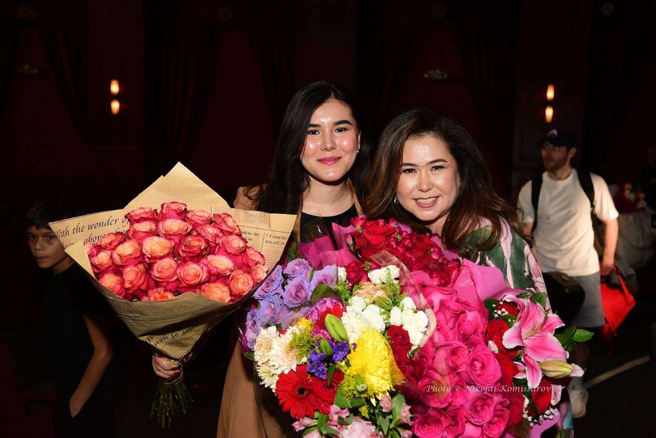 Two performers holding flower bouquets after a celebration