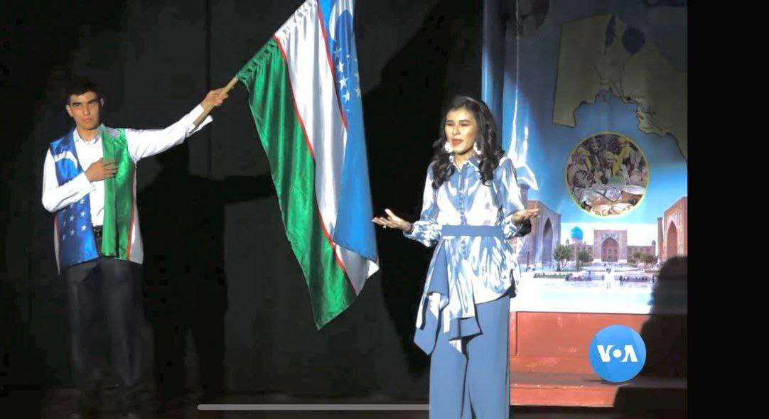 Stage performance with the flag of Uzbekistan raised before a projected backdrop