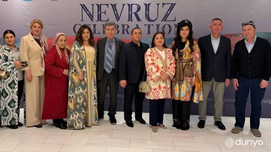 Guests gathered before a Nevruz celebration screen in traditional and formal dress
